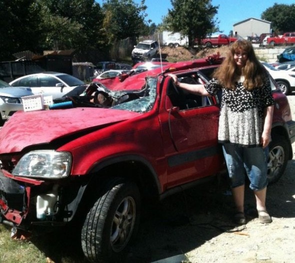 Mary Ellen Frazier stands beside her wrecked vehicle.