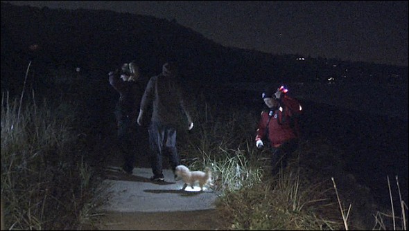 Police officers and firefighters rescue a couple and their dog stranded on a cliff.