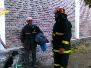 Firefighters rescuing homeless man and dog from rain storm.