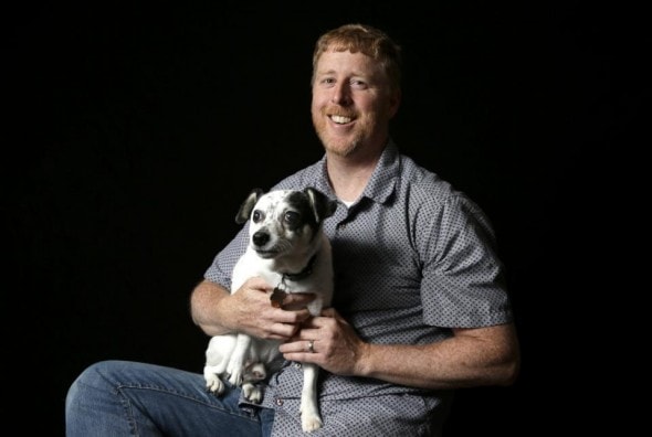 In this Monday, June 8, 2015 photo, photographer Fred Levy poses with his dog, a 12-year-old rat terrier named Toby, for a photograph at his home, in Maynard, Mass. Levy, a pet photographer, first heard about Black Dog Syndrome in a 2013 conversation at a dog park. Its a disputed theory that black dogs are the last to get adopted at shelters, perhaps because of superstition or a perception that theyre aggressive. The idea inspired Levy to take up a photo project on their behalf. (AP Photo/Steven Senne)